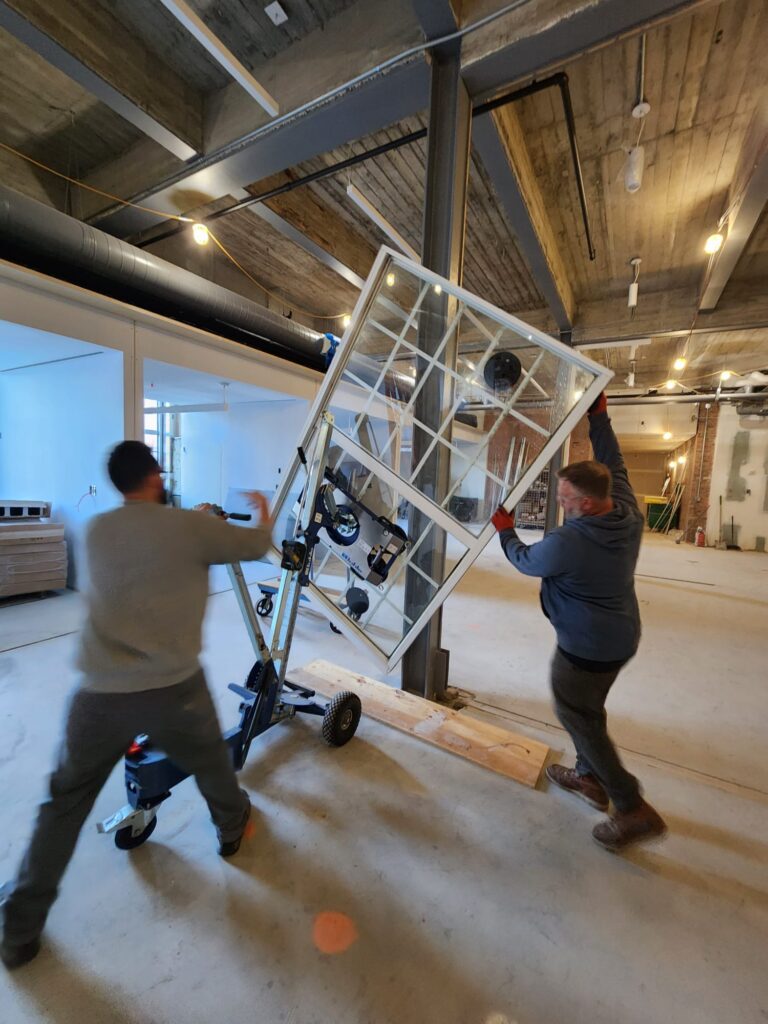 two workers are transporting a window on a special dolly before its installation