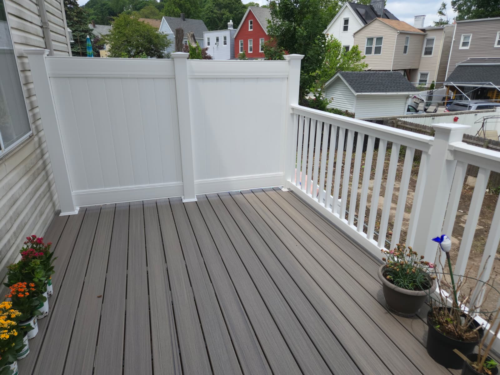 Gray composite deck with white railings and privacy fence on a Staten Island home.