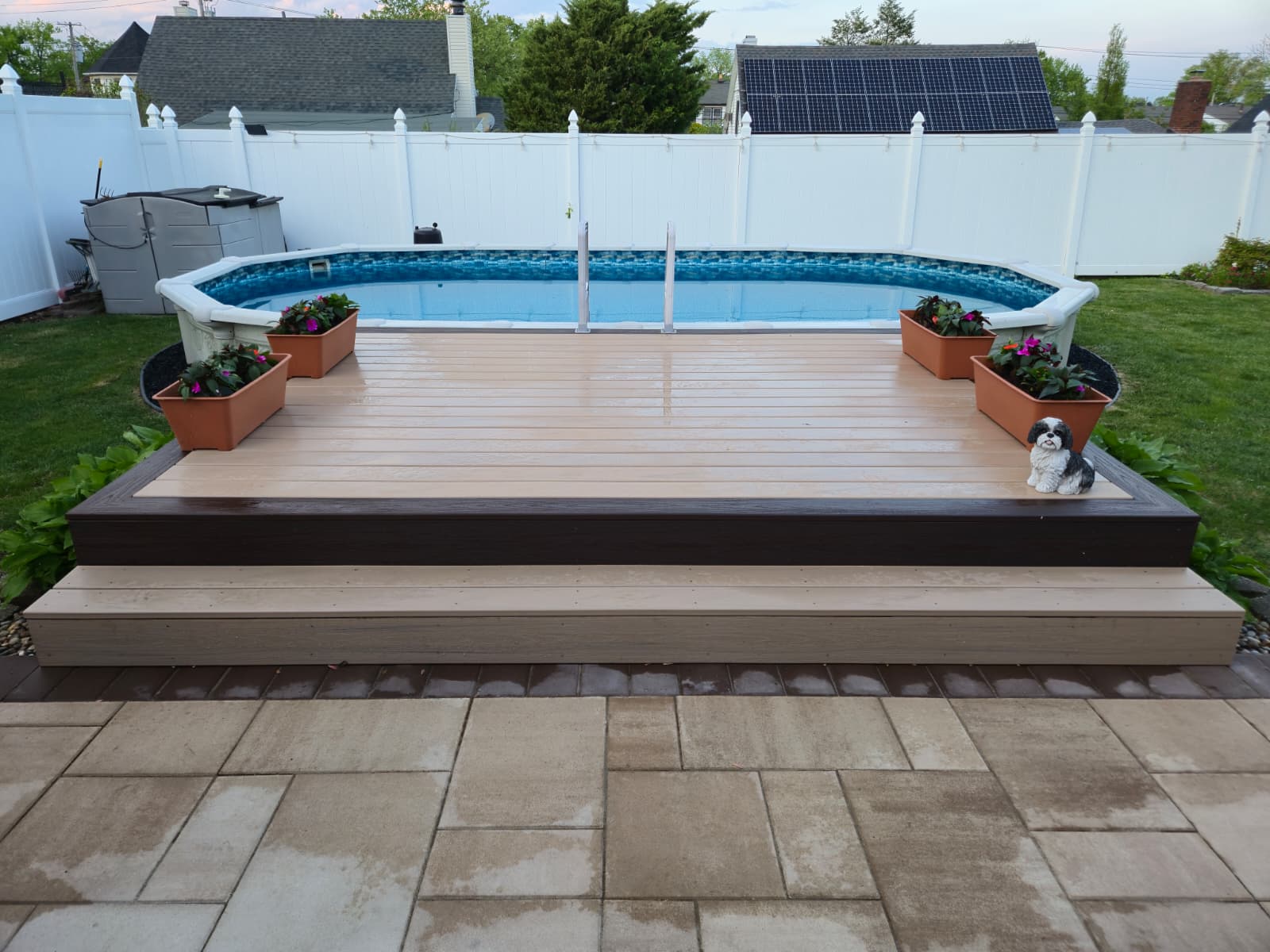 Composite deck platform around an above-ground pool with backyard patio access.